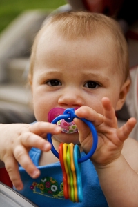 baby holding toy keys and sucking soother